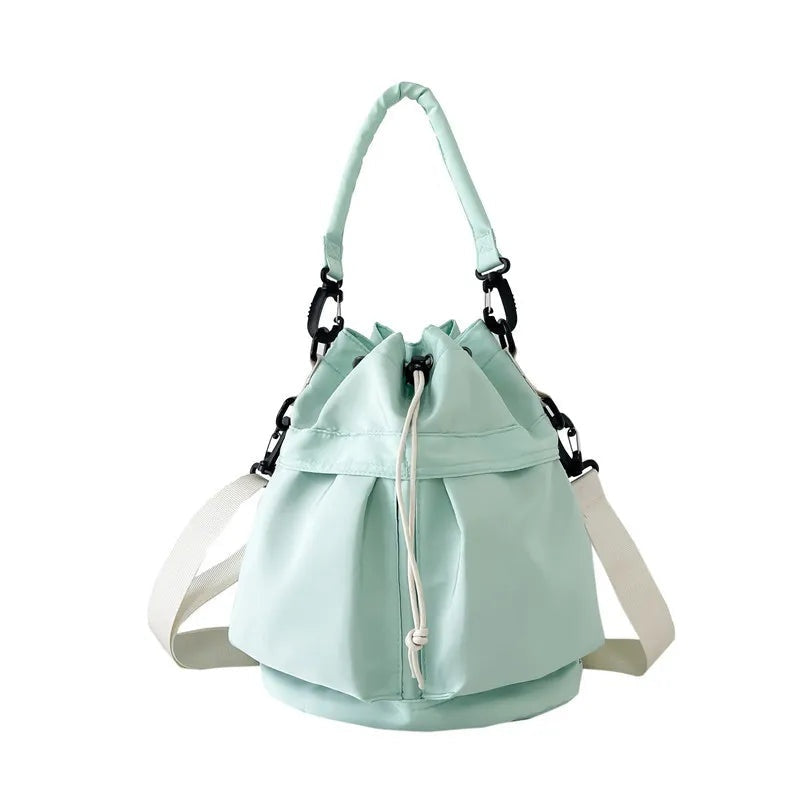 A medium mint-green nylon drawstring bucket bag with a softly gathered opening, top handle, side straps, and a structured rounded base.