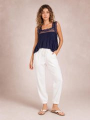 Model stands in white drawstring paperbag waist cropped joggers with a relaxed silhouette, side pockets, and gathered ankle cuffs.