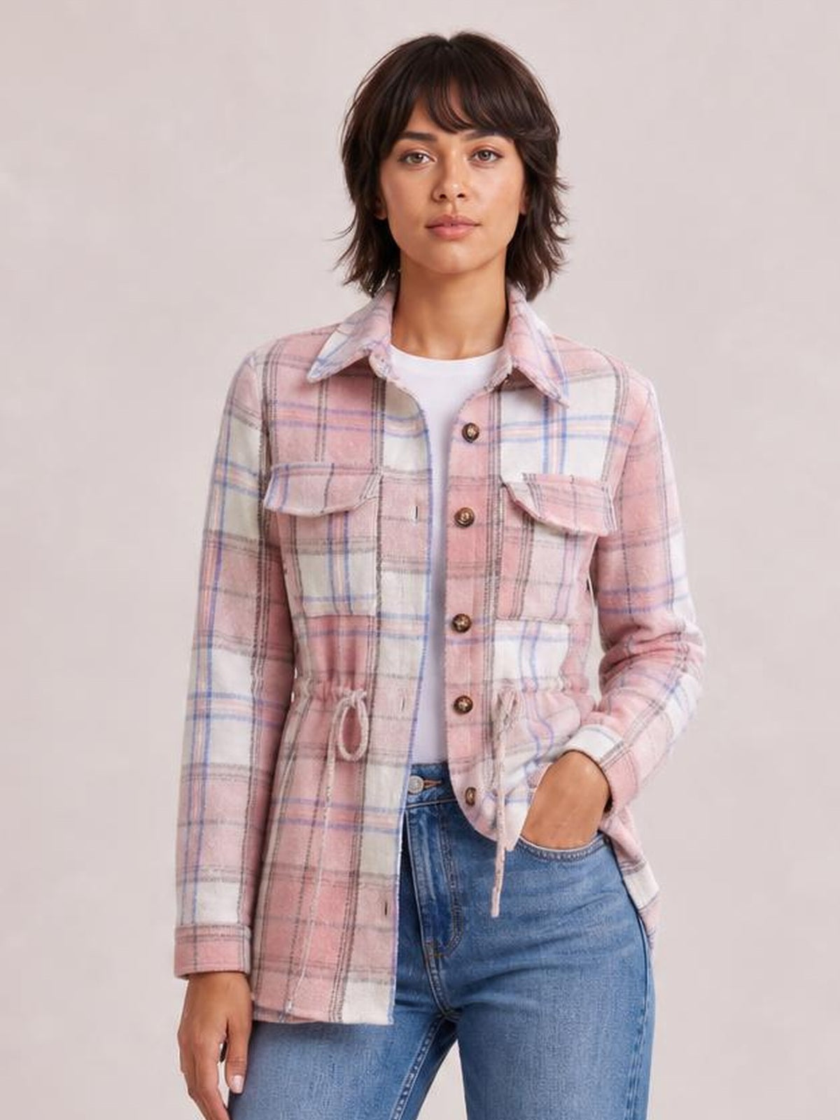 Model wearing a pink and white plaid button-up jacket with a collared silhouette, chest pockets, long sleeves, and a visible waist drawstring.