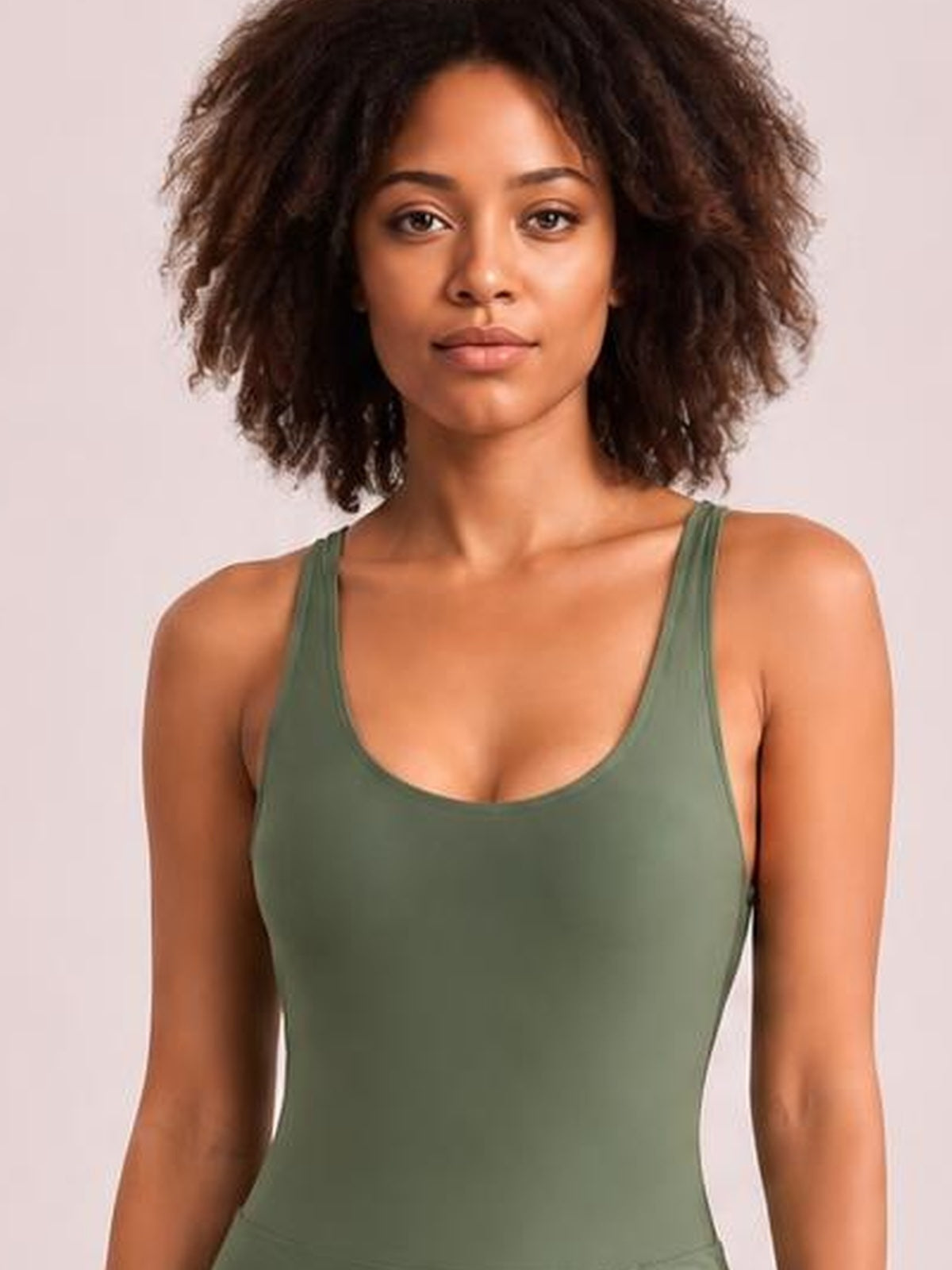 Model wears an olive green one-piece swimsuit with a scoop neck, wide straps, and a smooth, fitted silhouette.