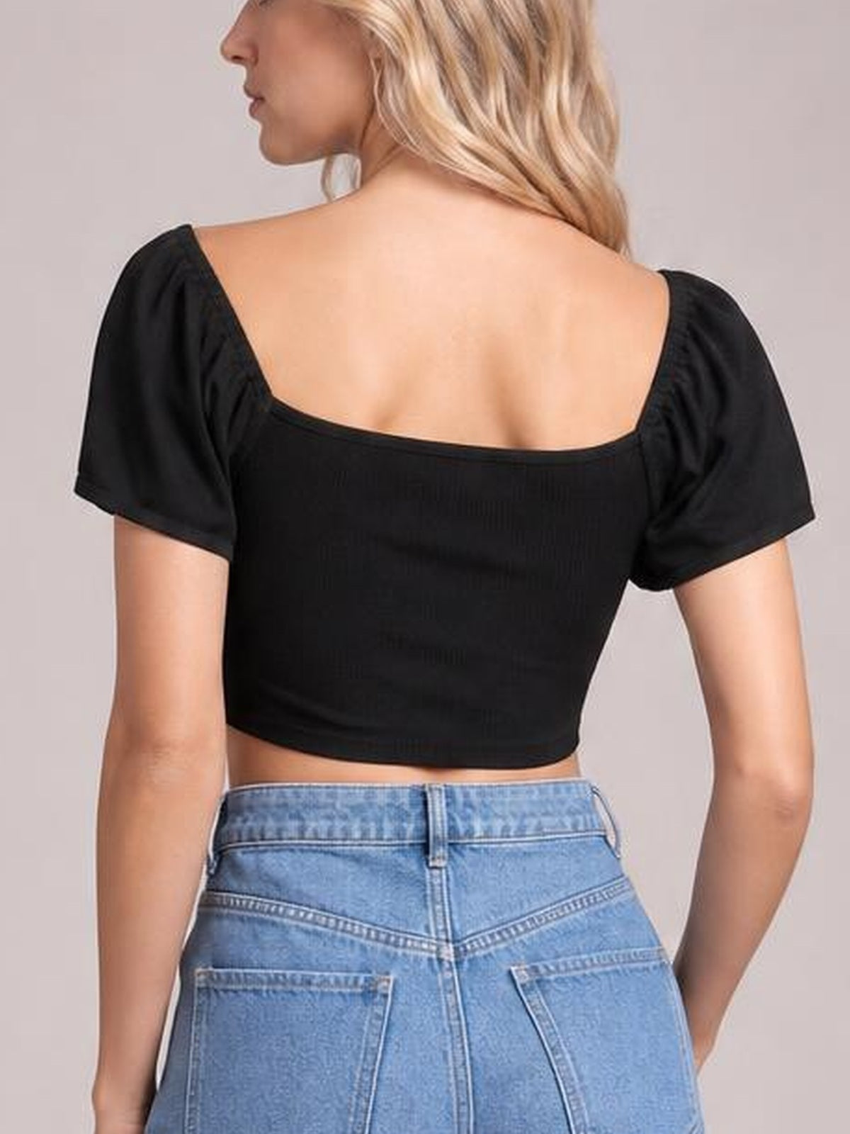 A model shown from behind wears a black short-sleeve crop top with a square back neckline and fitted silhouette.
