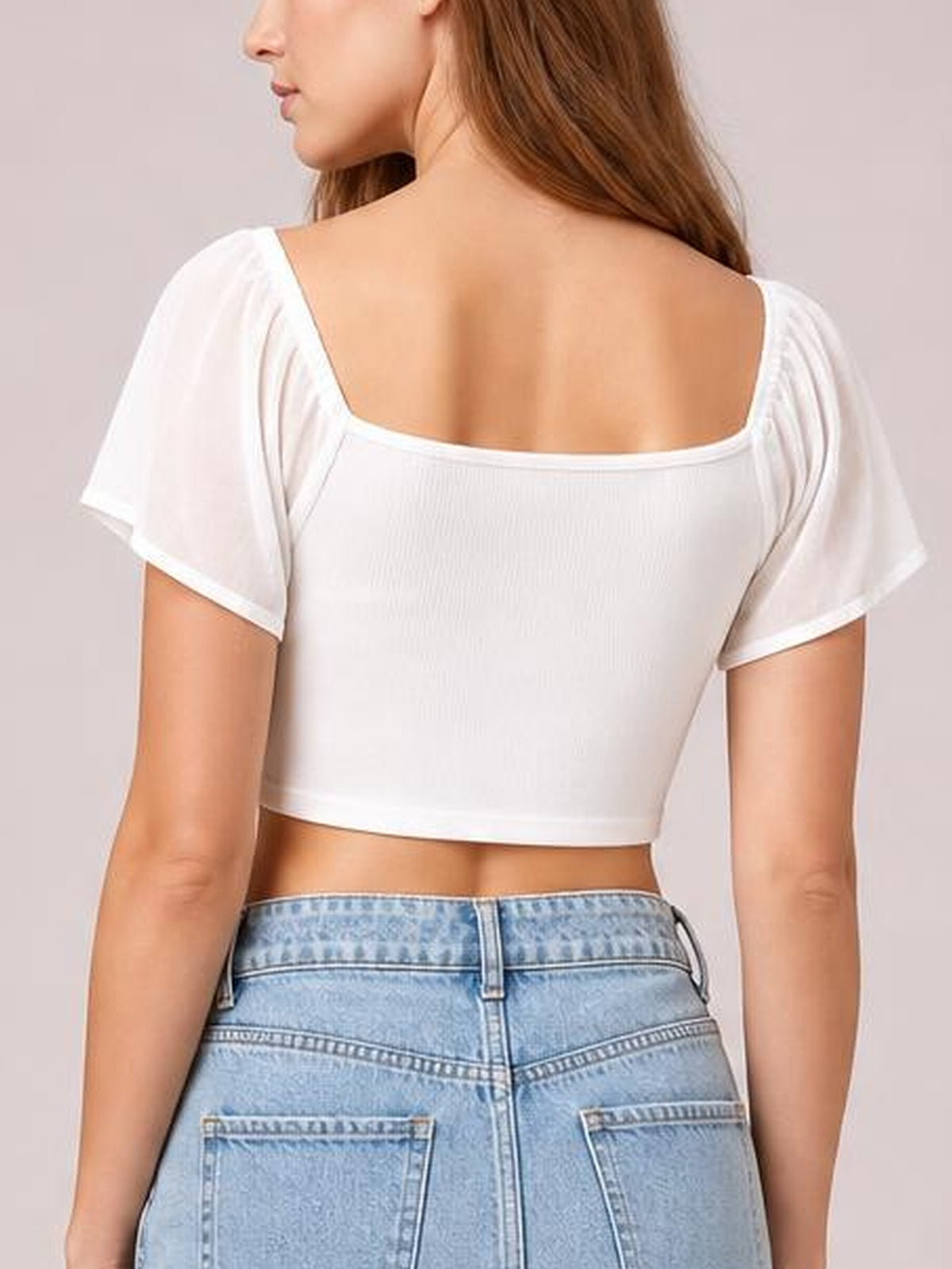 Model shown from the back wearing a white short-sleeve crop top with a square neckline, fitted silhouette, and exposed midriff.