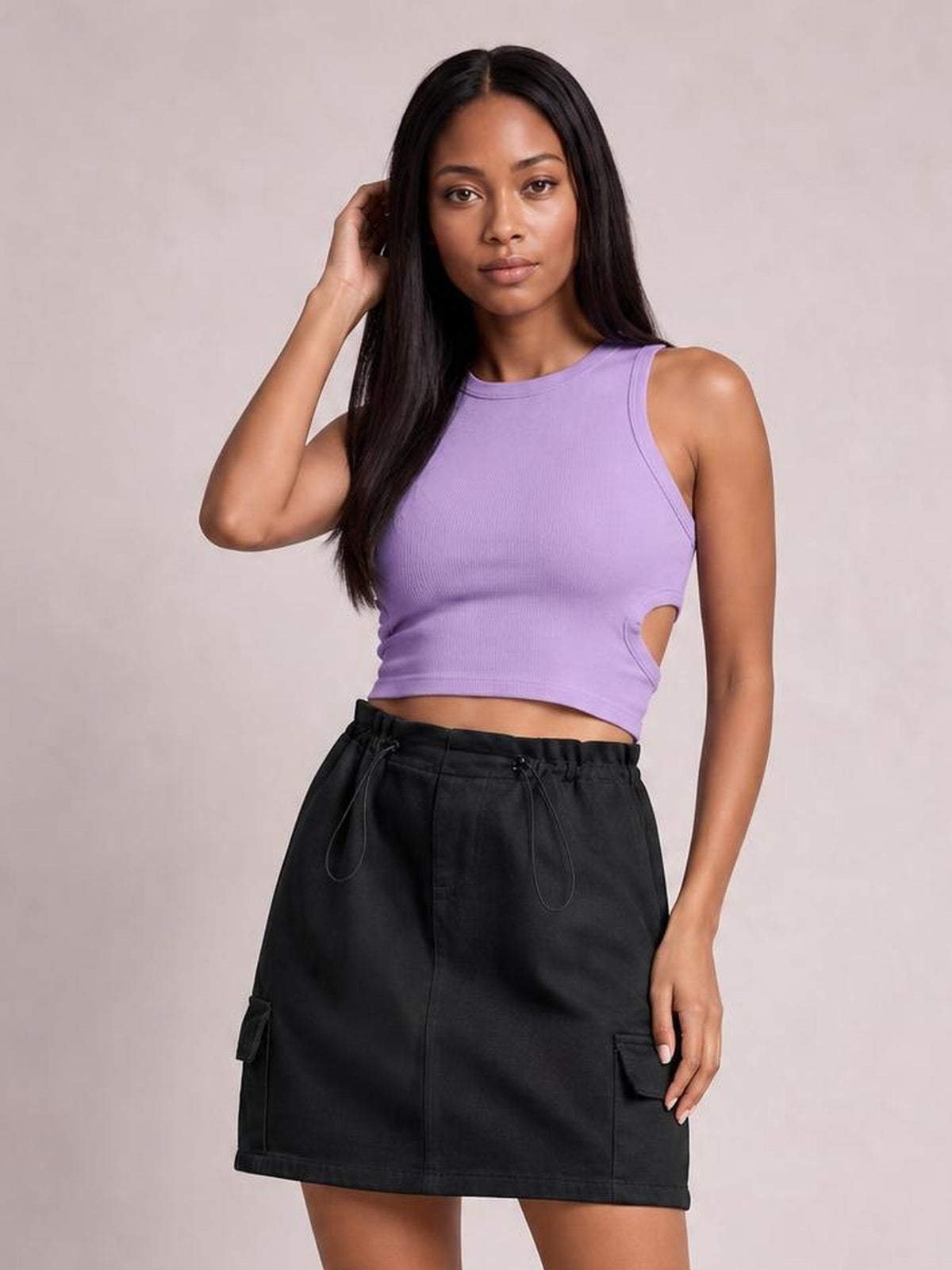 Model poses with one hand in her hair, wearing a black denim mini skirt with a drawstring waist, straight hem, front seam, and cargo-style pockets.