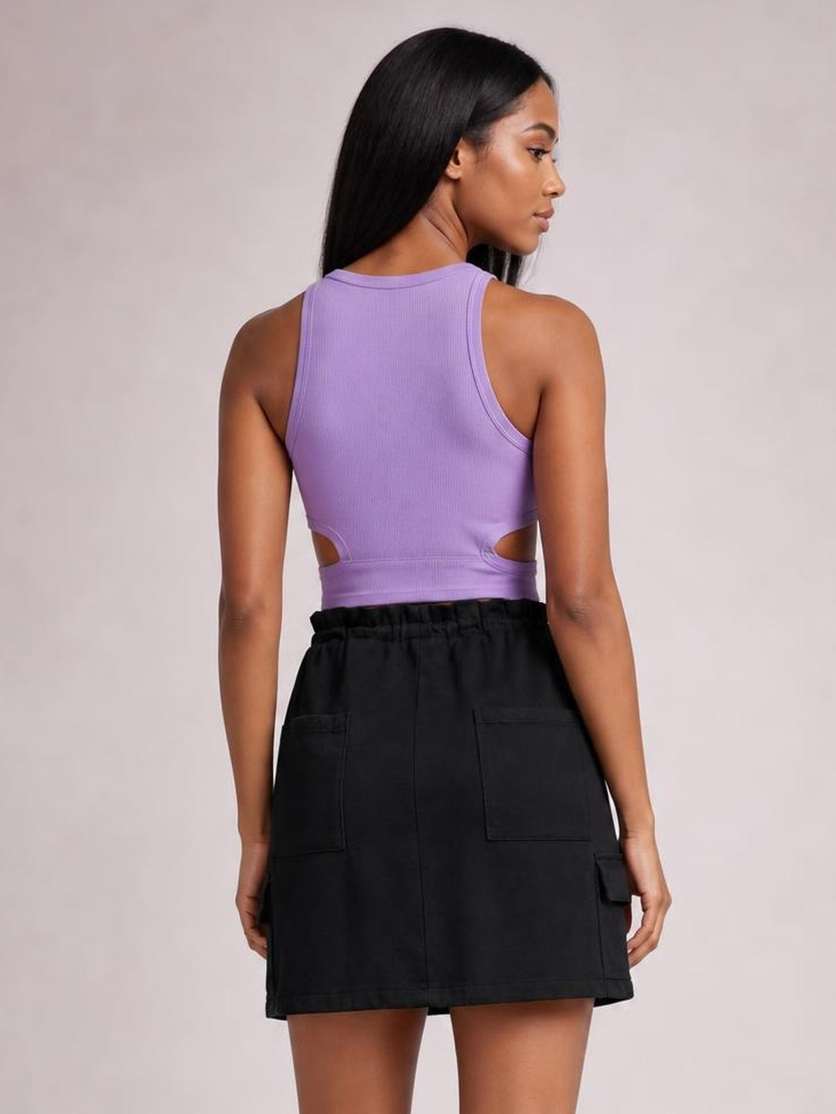 Back view of a model wearing a black drawstring denim mini skirt with a straight hem, relaxed silhouette, and multiple utility pockets.