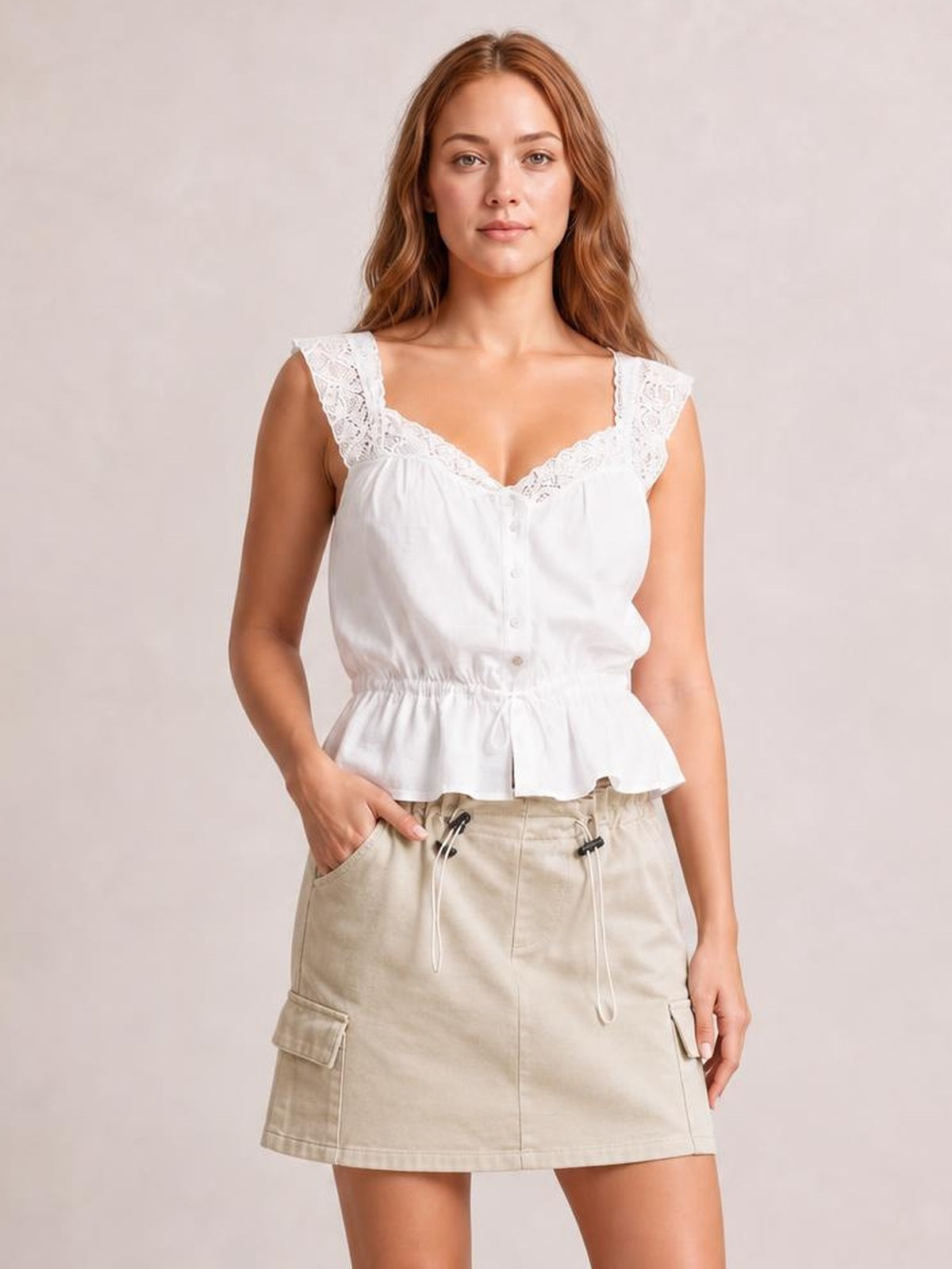 Model stands in a beige drawstring mini skirt with a straight hem, front pockets, and cargo-style side pockets for a casual silhouette.