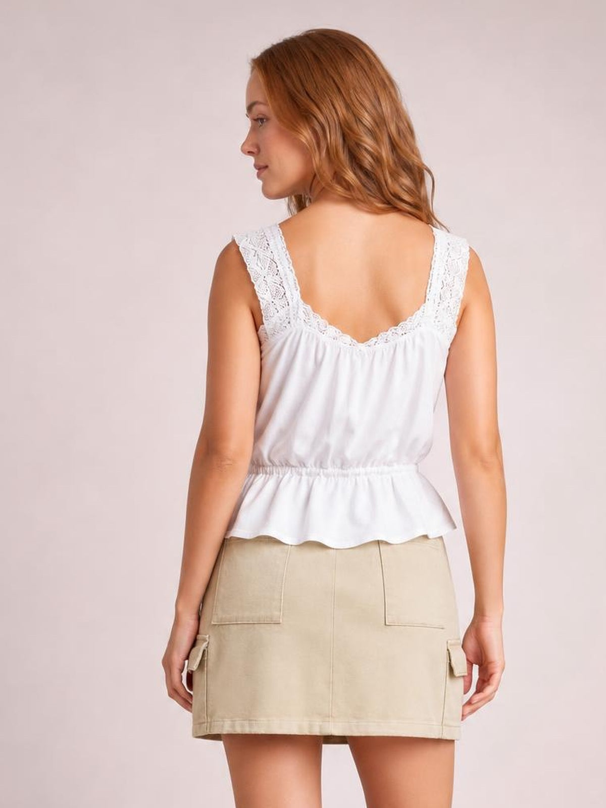 Model shown from the back wearing a beige denim mini skirt with a straight hem, center seam, large patch pockets, and side cargo pockets.