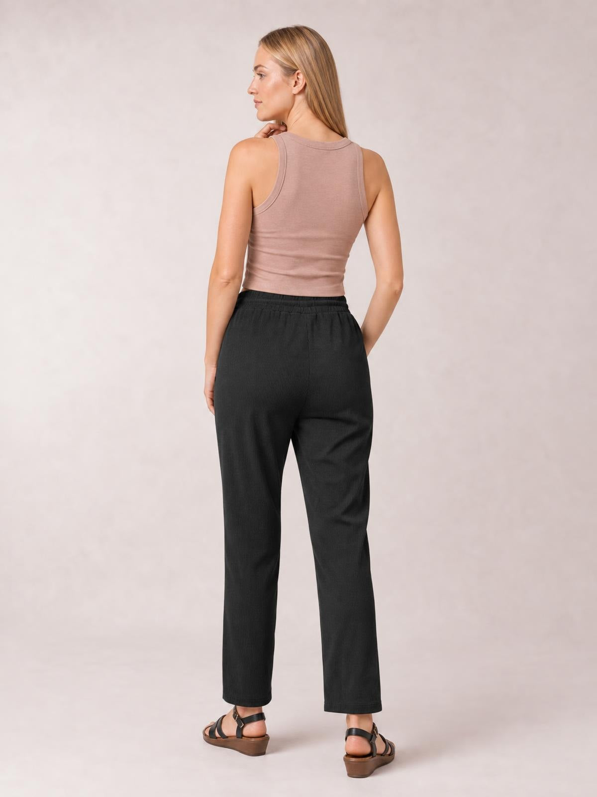 Model shown from behind in black drawstring straight pants with pockets, an elasticized waist, relaxed fit, and full-length straight legs.