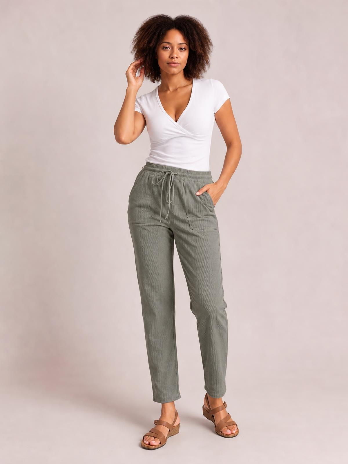 A model poses in olive-gray straight pants with a drawstring waist, side pockets, and a relaxed silhouette, one hand resting in a pocket.