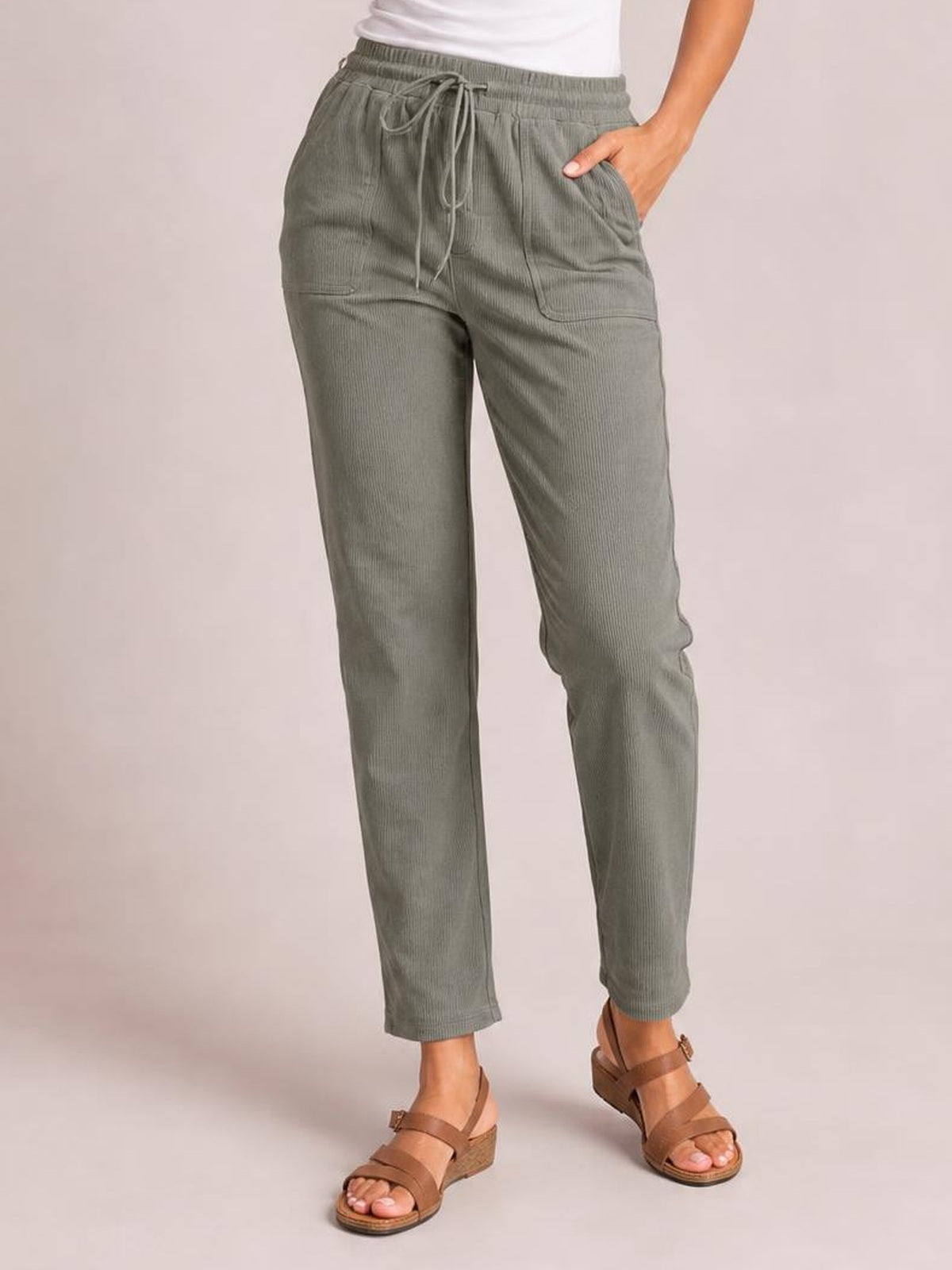 Model wearing gray-green drawstring straight pants with an elastic waist, side pockets, and ankle-length legs, standing in brown wedge sandals.