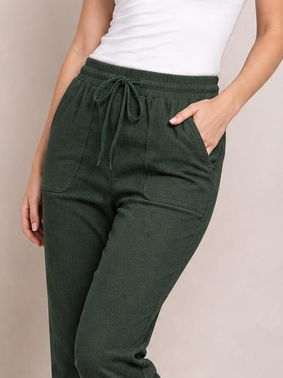 Model wearing dark green drawstring straight pants with an elastic waist, visible side pockets, and a relaxed straight-leg silhouette.