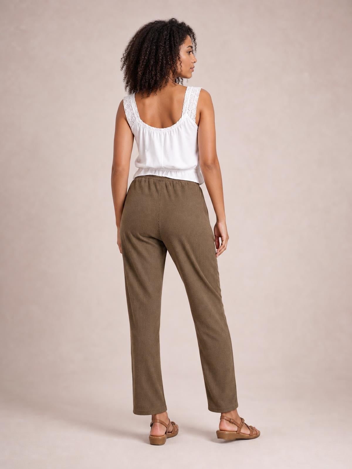 A model stands in a back-facing pose wearing brown drawstring straight pants with a relaxed, ankle-length silhouette and gathered elastic waist.