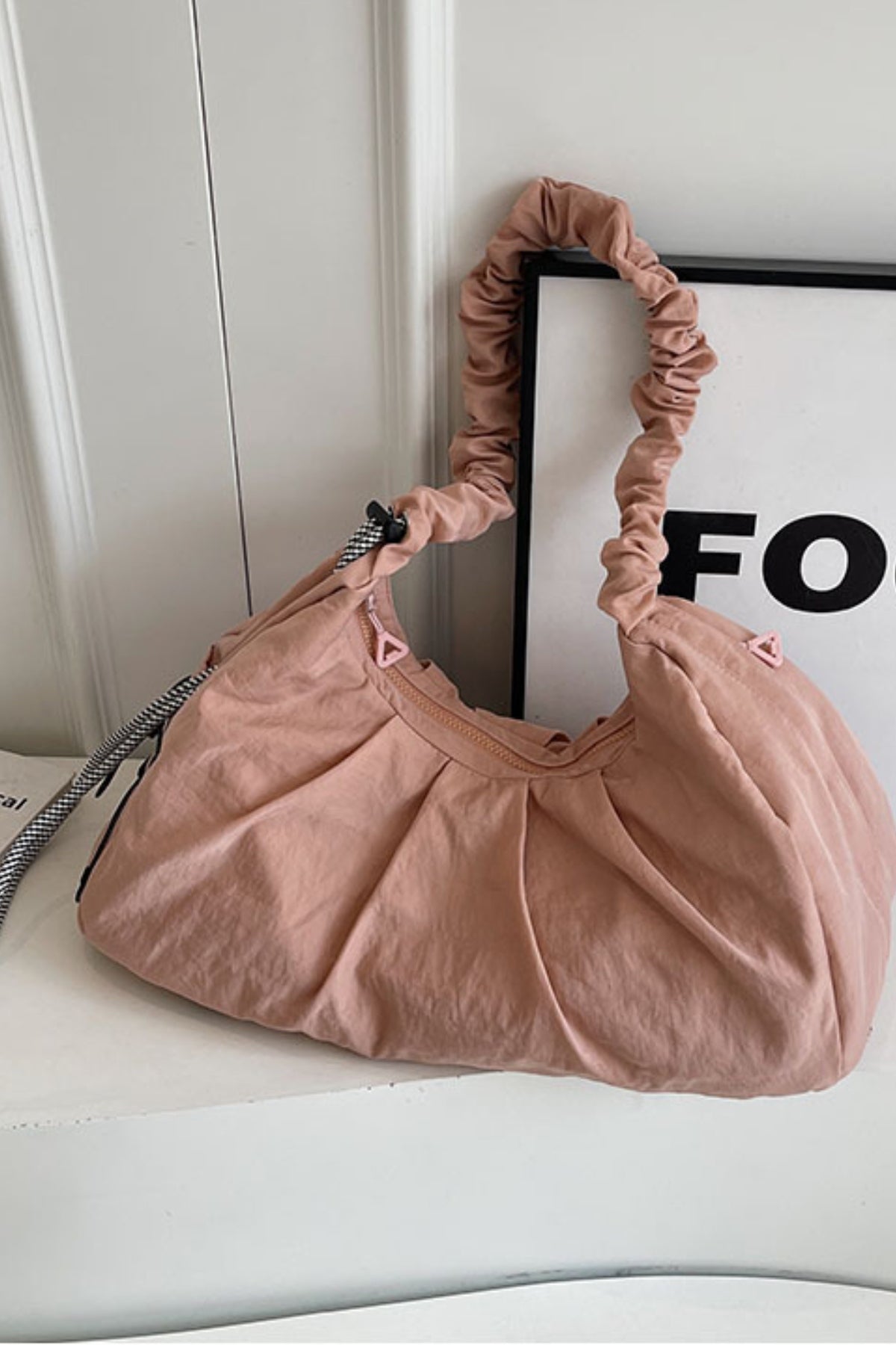 Large blush-pink ruched crossbody bag with a softly slouchy silhouette, gathered drawstring strap, roomy construction, and relaxed cloth finish.