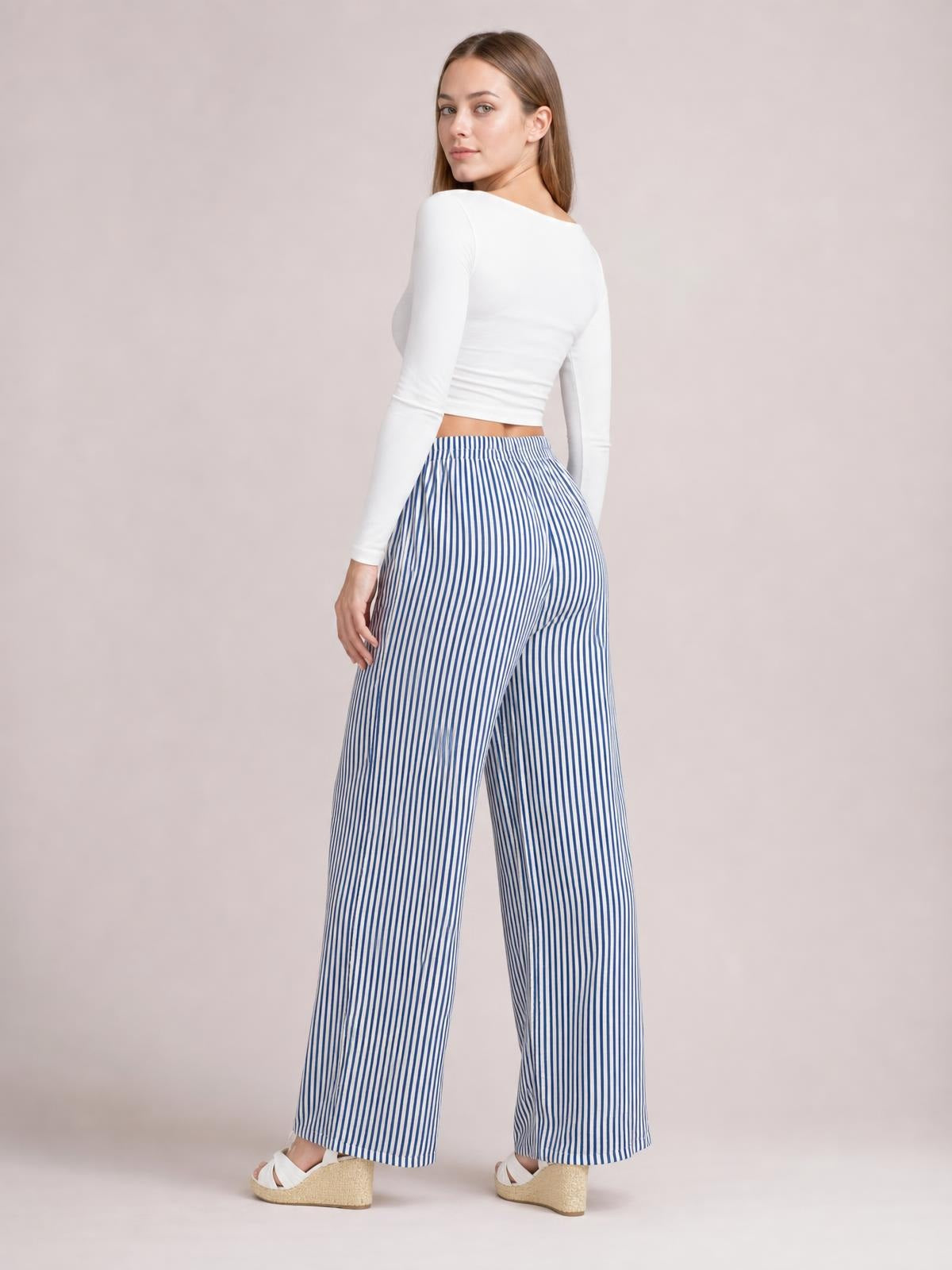 Model poses in blue-and-white striped pants with an elastic drawstring waist, wide-leg silhouette, and visible side pockets.