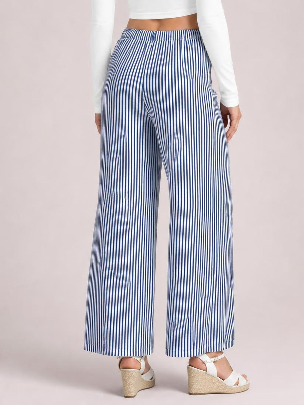 Model wearing blue-and-white vertically striped pants with an elastic drawstring waist, relaxed wide-leg silhouette, and visible side pockets.