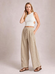 Model poses in beige-and-white striped drawstring elastic waist pants with wide-leg silhouette, side pockets, and a relaxed casual fit.