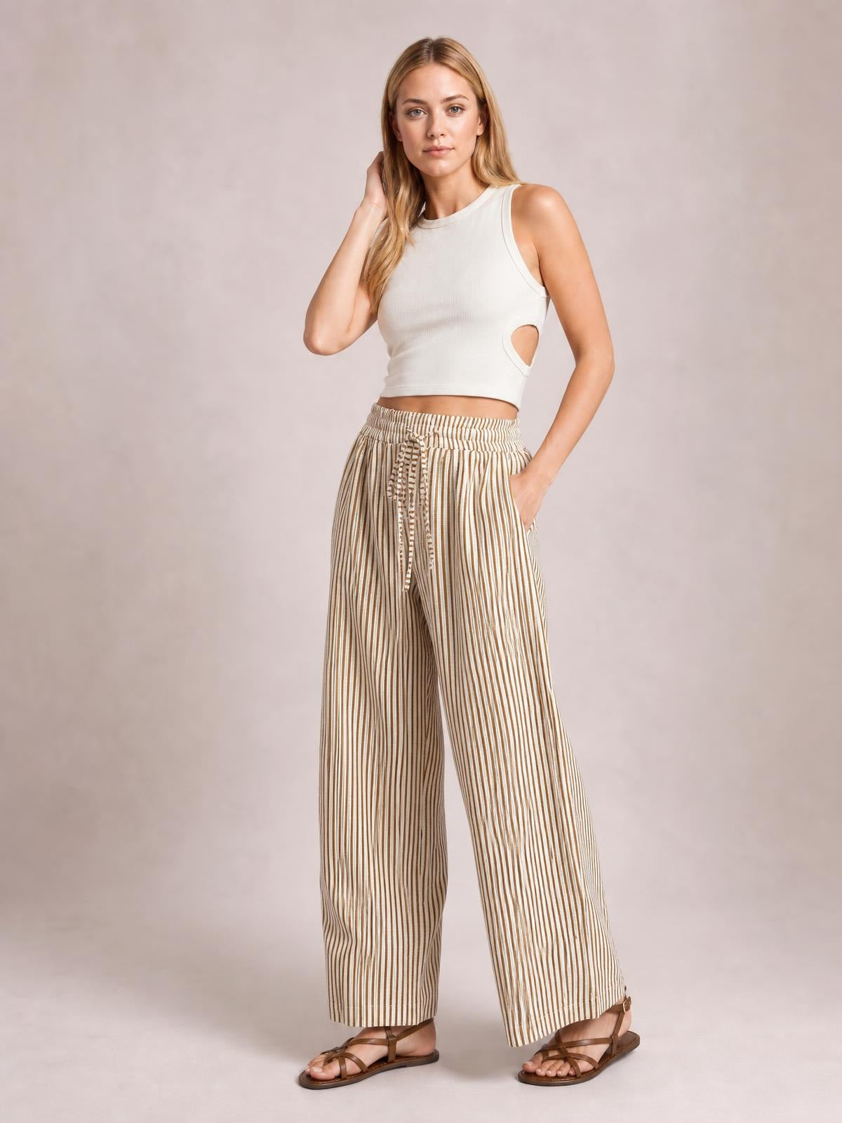 Model poses in beige-and-white striped drawstring elastic waist pants with wide-leg silhouette, side pockets, and a relaxed casual fit.
