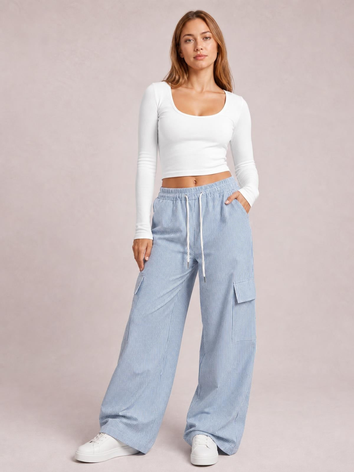 Model stands facing forward in light blue striped wide-leg cargo pants with a drawstring waist, multiple pockets, and a relaxed silhouette.