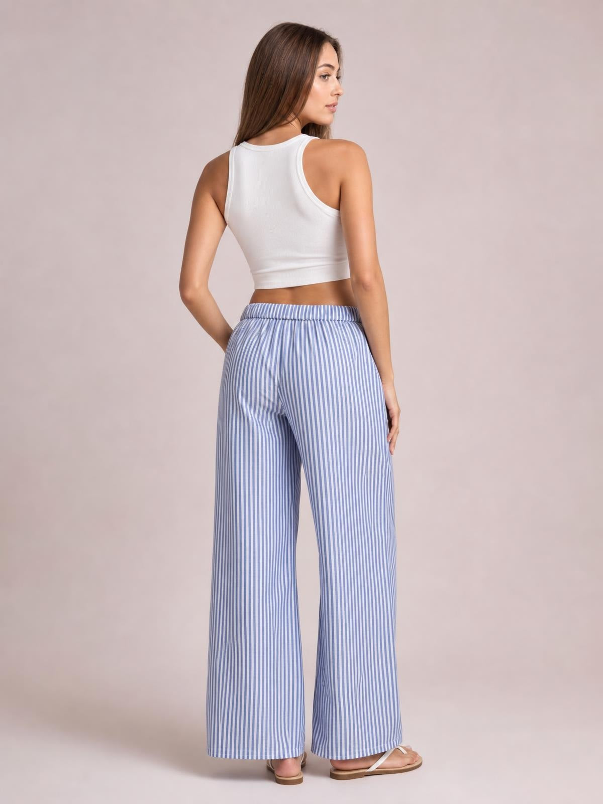 Model shown from behind in blue-and-white striped drawstring pants with a relaxed high waist and wide-leg silhouette.