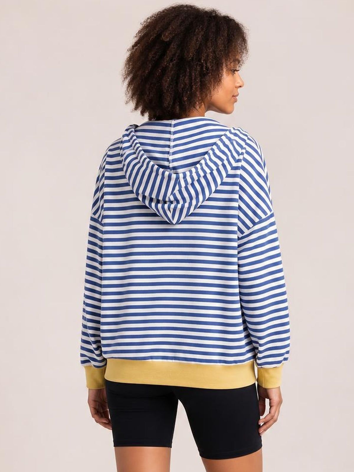 Model shown from the back wearing a blue-and-white striped zip-up hoodie with long sleeves, a drawstring hood, and a relaxed silhouette.