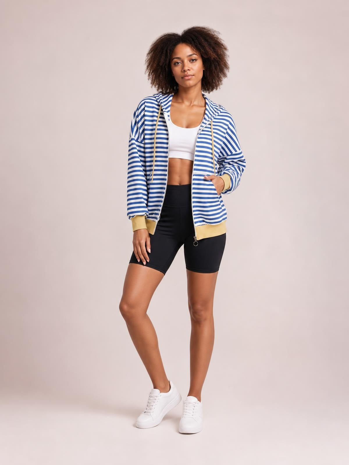A model poses with one hand in the pocket, wearing a blue-and-white striped zip-up long-sleeve hoodie with a drawstring hood and relaxed silhouette.