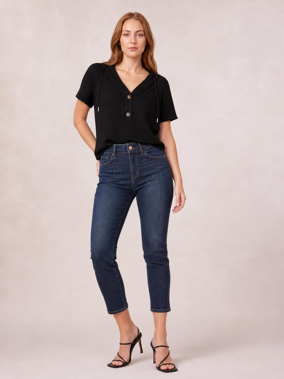A model poses in a black waffle-knit short-sleeve hooded top with drawstring cords, button front, and a relaxed straight silhouette, one hand at her hip.
