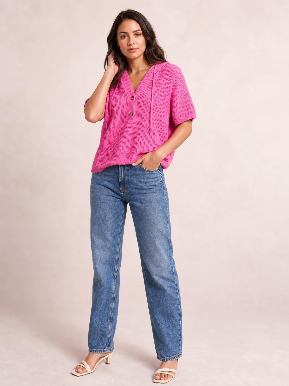Model poses in a relaxed pink waffle-knit short-sleeve hooded top with drawstrings, buttoned V-neck, and a loose casual silhouette.