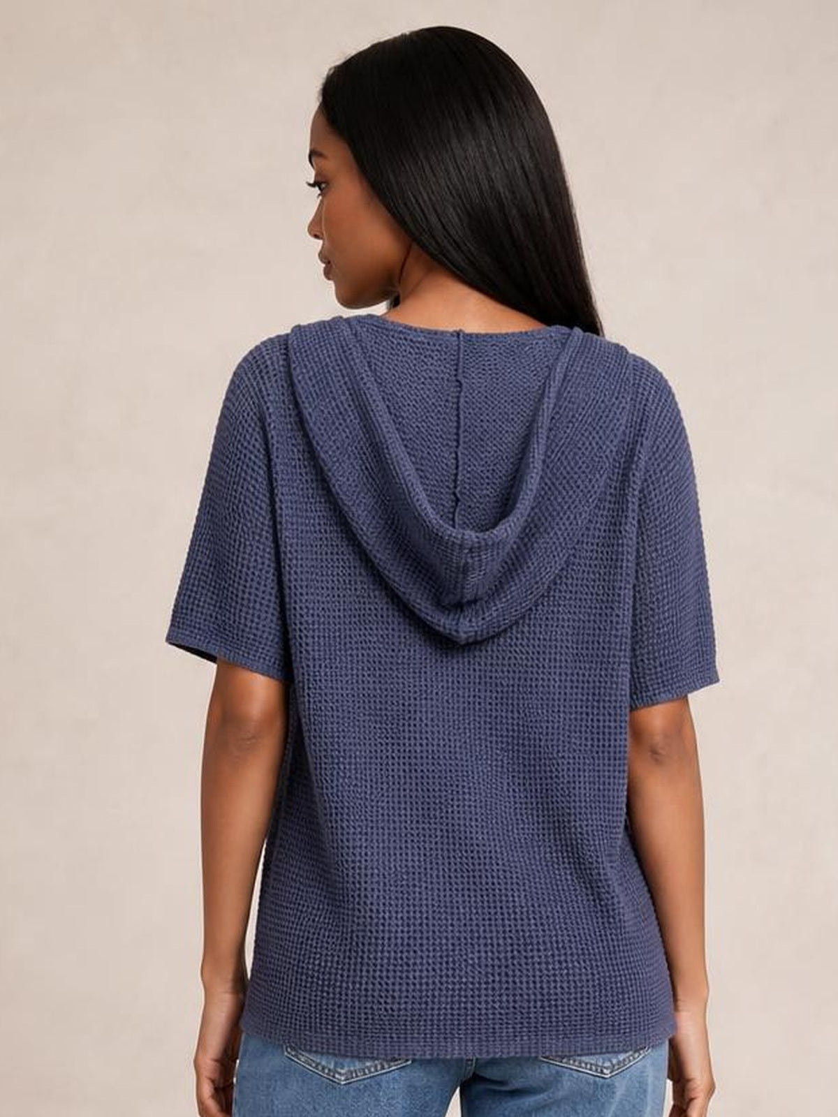 Model shown from the back wearing a navy waffle-knit short-sleeve hooded top with a relaxed, slightly loose silhouette and draped hood.