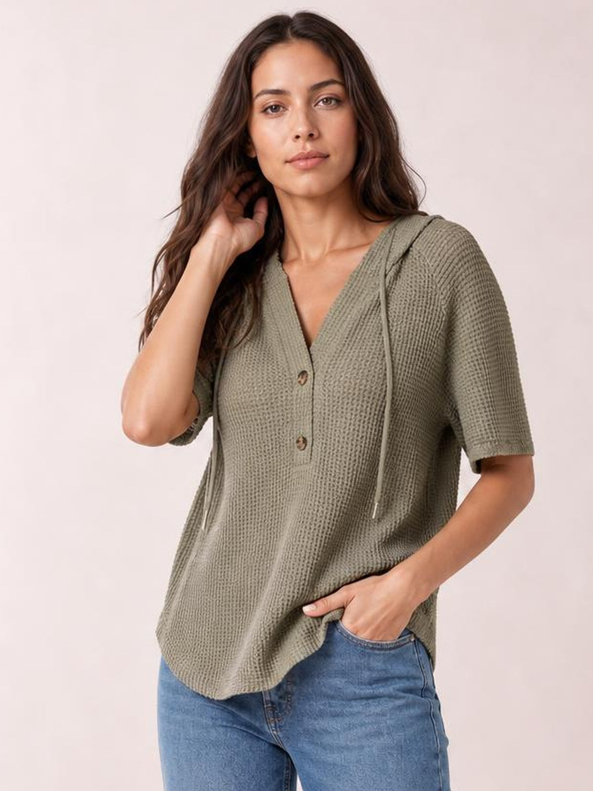 Model poses in a relaxed olive waffle-knit short-sleeve hooded top with drawstring ties, buttoned V-neck, and a loose casual silhouette.
