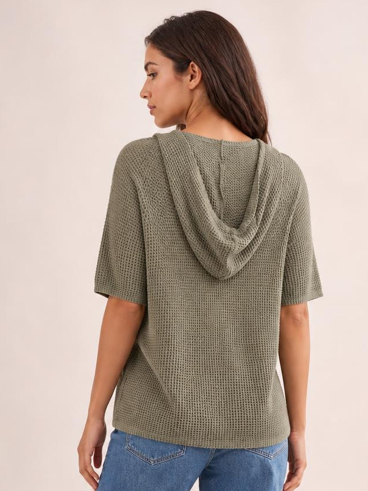 Model shown from the back in a relaxed olive waffle-knit short-sleeve hooded top with a draped drawstring hood and straight silhouette.