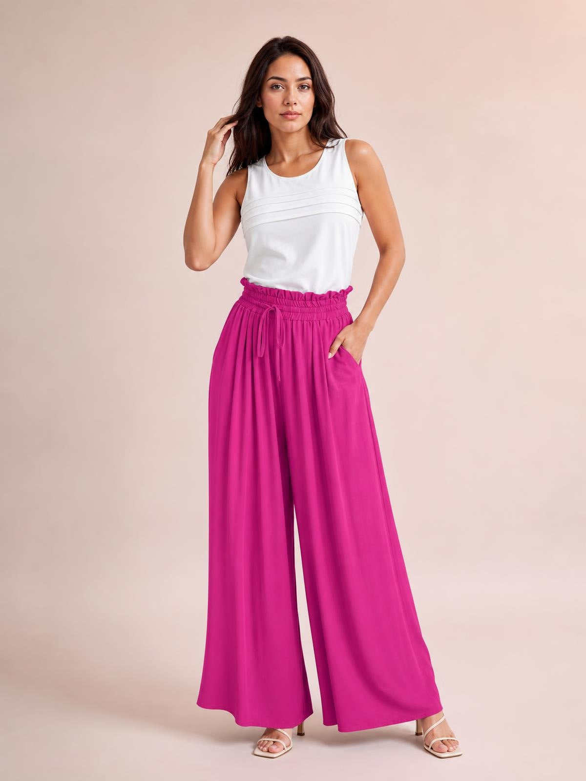 Model poses in vibrant magenta drawstring wide leg pants with a gathered waistband, flowing silhouette, and side pockets, with one hand tucked into a pocket.