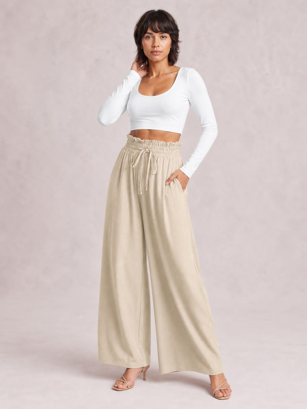 A model poses in beige drawstring wide-leg pants with an elastic waistband, flowing silhouette, straight hems, and visible side pockets.