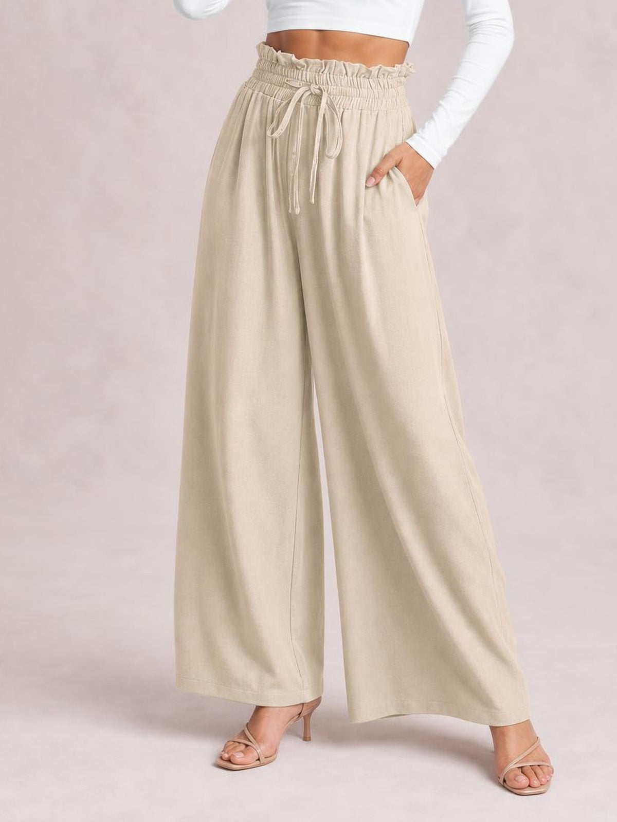 Model wears beige drawstring wide leg pants with a flowy silhouette, gathered waistband, front pockets, and relaxed full-length legs.
