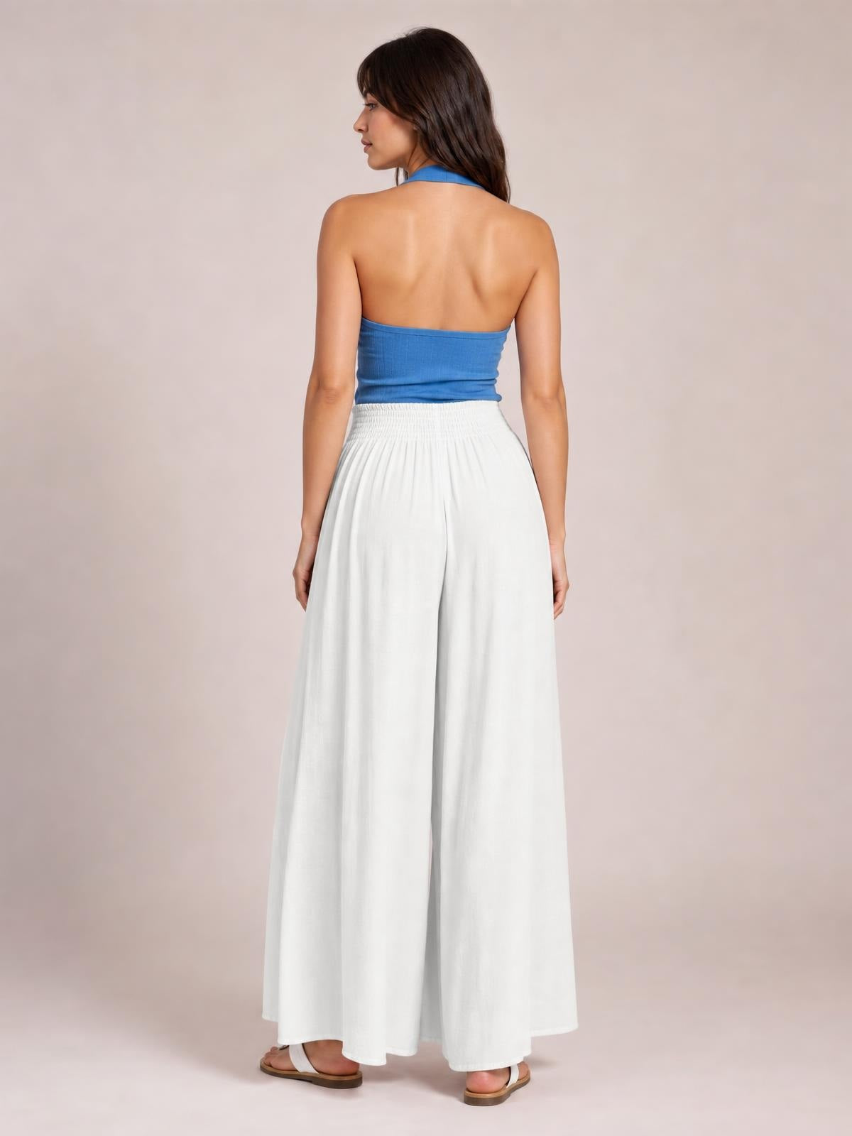Model shown from behind wearing white wide-leg pants with a high elastic waistband, flowing silhouette, and full-length drape.