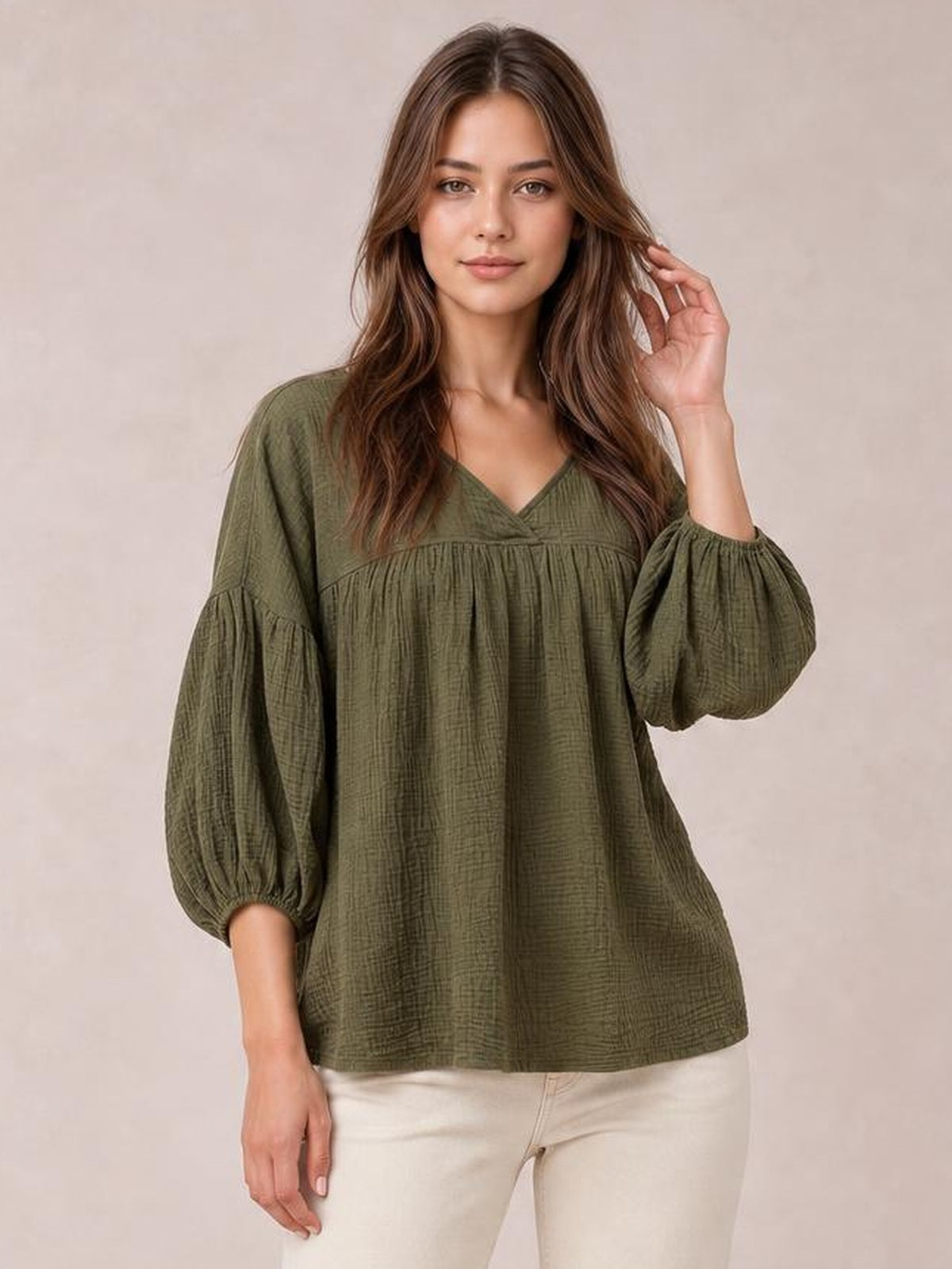 Model poses in an olive green solid V-neck blouse with dropped shoulders, long gathered balloon sleeves, textured tiered construction, and a relaxed long silhouette.