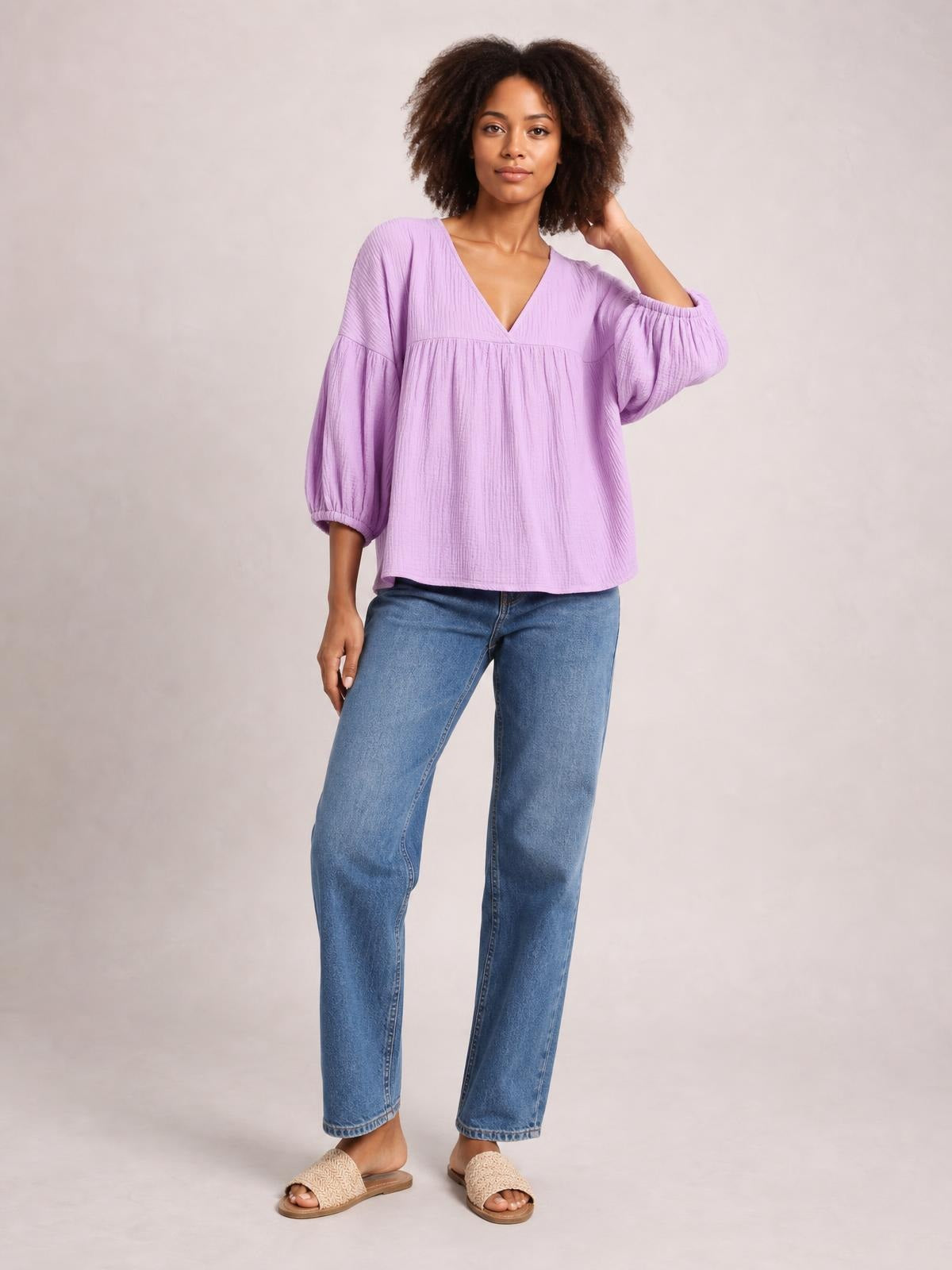 Model wears a lavender dropped shoulder V-neck blouse with a long, loose silhouette, textured fabric, gathered sleeves, and elastic cuffs.