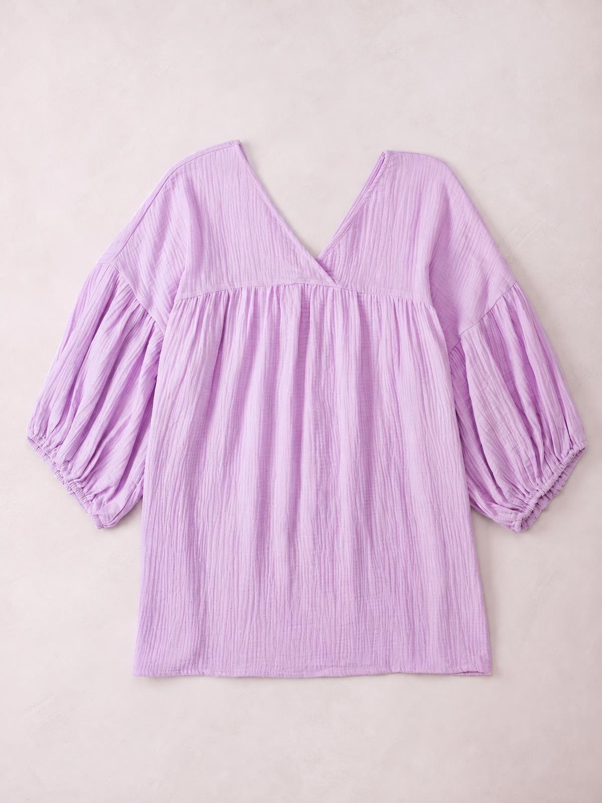 Lilac solid blouse with a V-neckline, dropped shoulders, long voluminous sleeves, gathered waist seam, and a relaxed long silhouette.