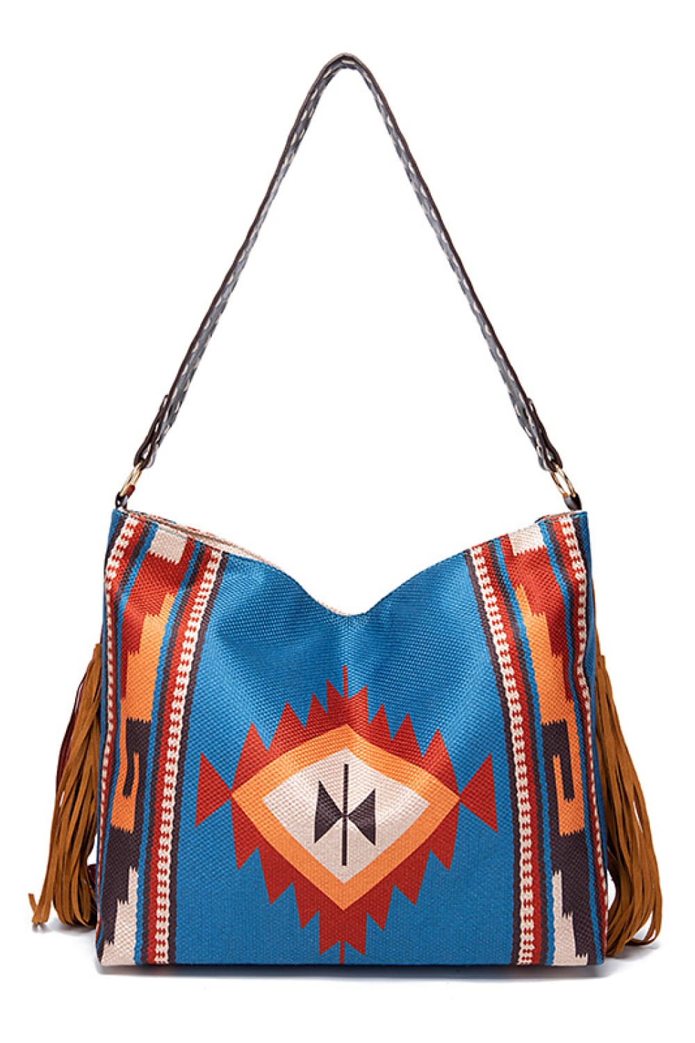 Oversize geometric canvas tote bag with a rectangular silhouette, vivid blue multicolor woven pattern, long shoulder strap, and fringe detailing along the sides.