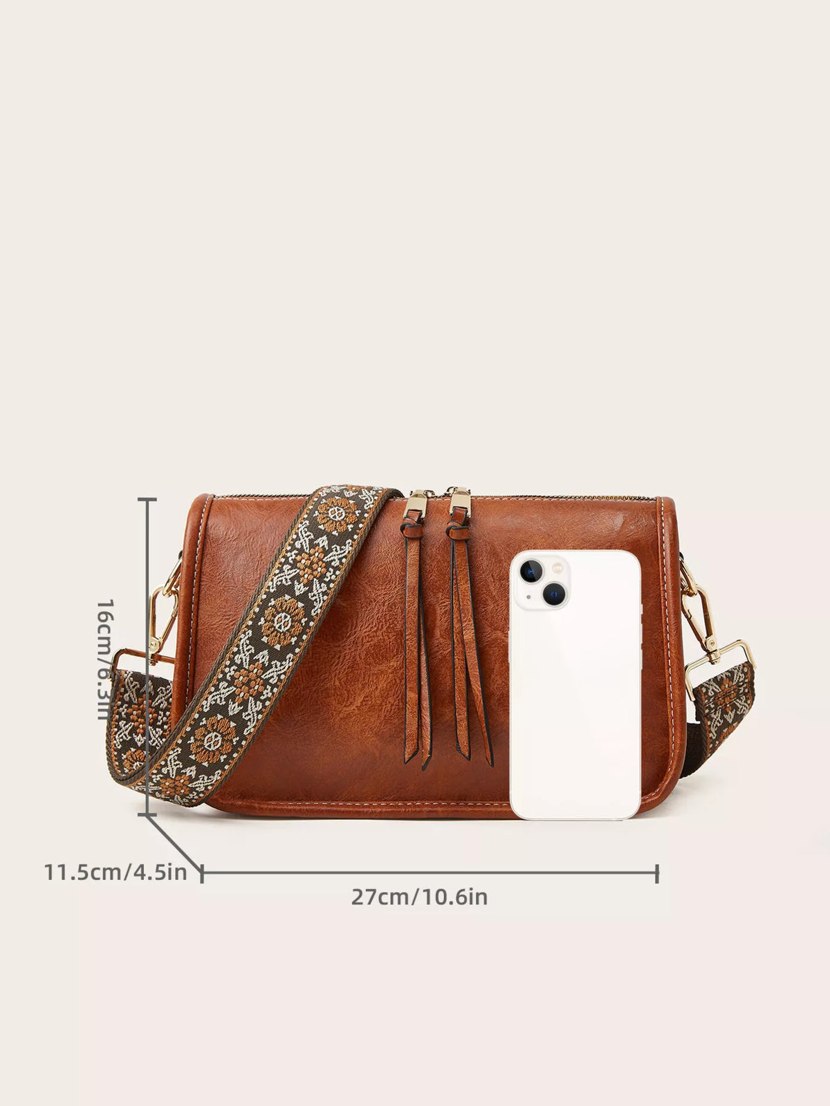 Small vintage-style brown PU leather crossbody bag with a rectangular silhouette, zip-top closure, decorative ties, and a patterned adjustable strap.