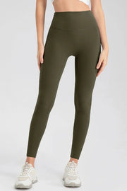 A model stands with hands at her sides wearing olive green high-waist skinny active pants with a smooth, fitted ankle-length leg.