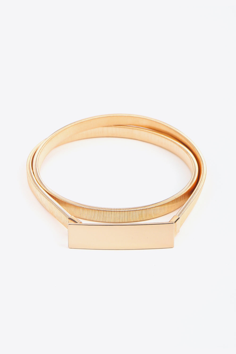 Gold-tone elastic iron skinny belt with a sleek narrow band and clean rectangular buckle, coiled to show its flexible construction.