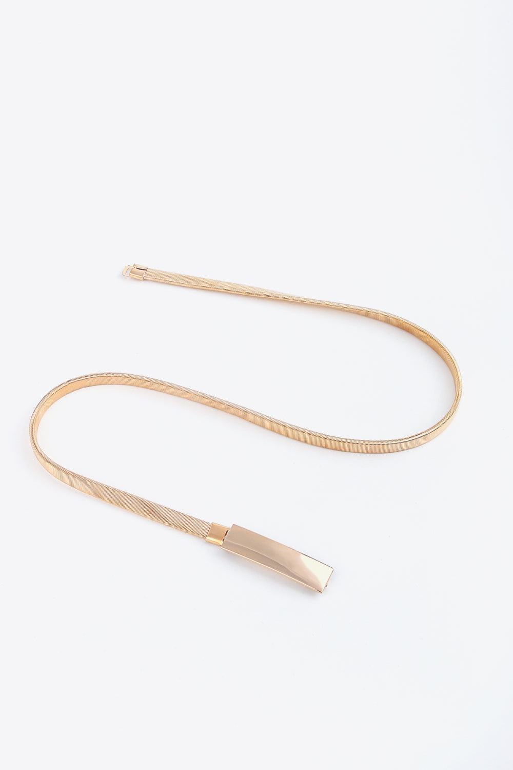 A rose-gold elastic iron skinny belt is shown laid flat, featuring a slender flexible band and polished rectangular buckle with a streamlined silhouette.