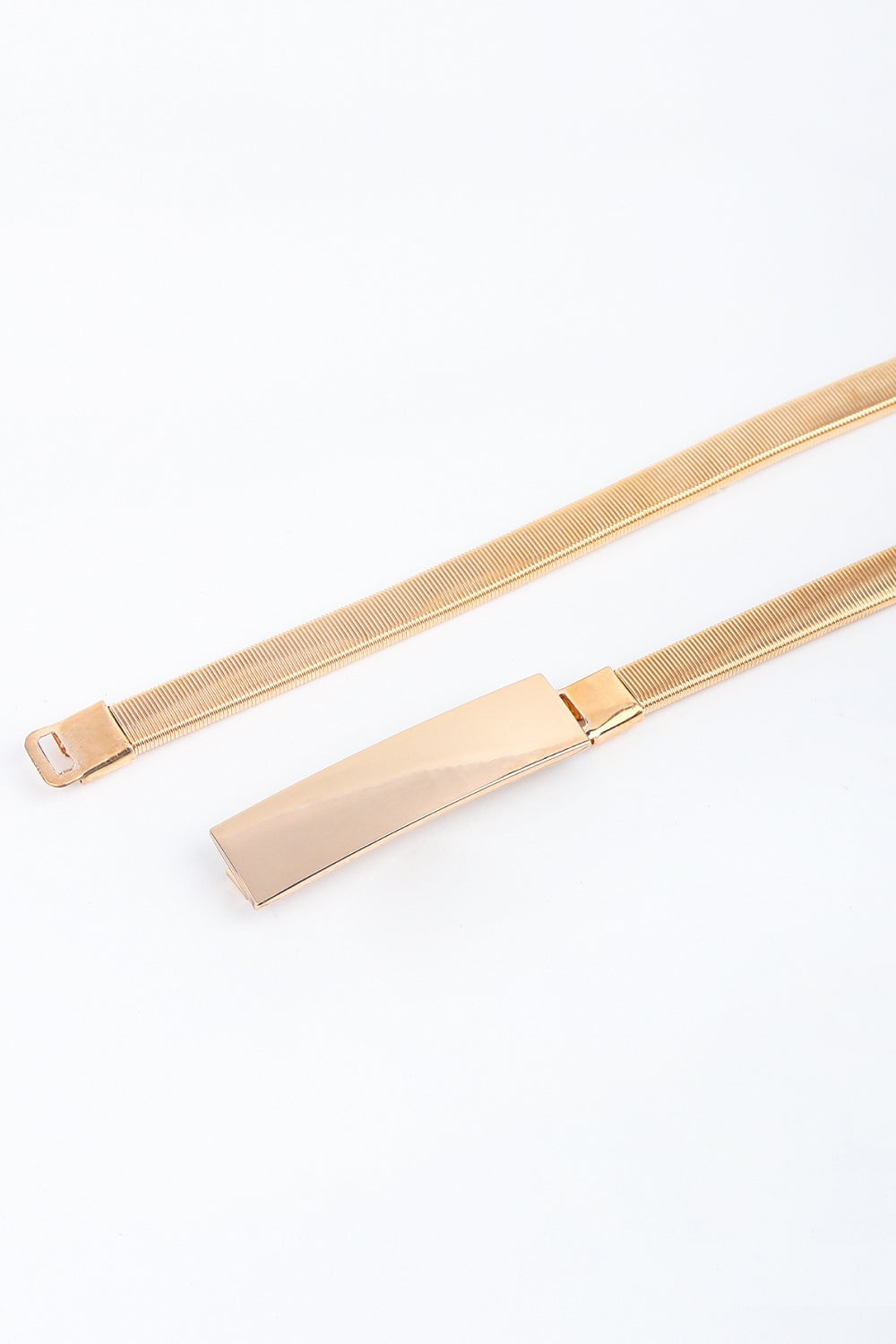 Elastic iron skinny belt in a metallic gold tone features a finely ribbed stretch band and sleek rectangular buckle.