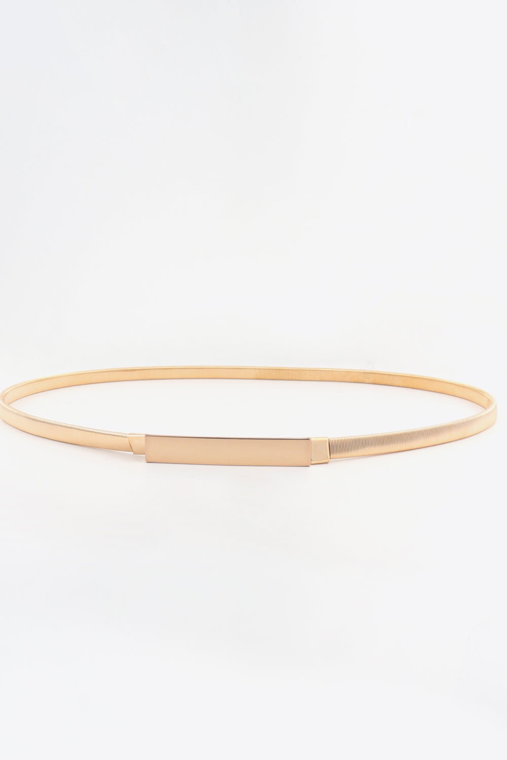 A gold-tone elastic iron skinny belt with a slender ribbed band and clean rectangular buckle, shown in a relaxed oval shape.