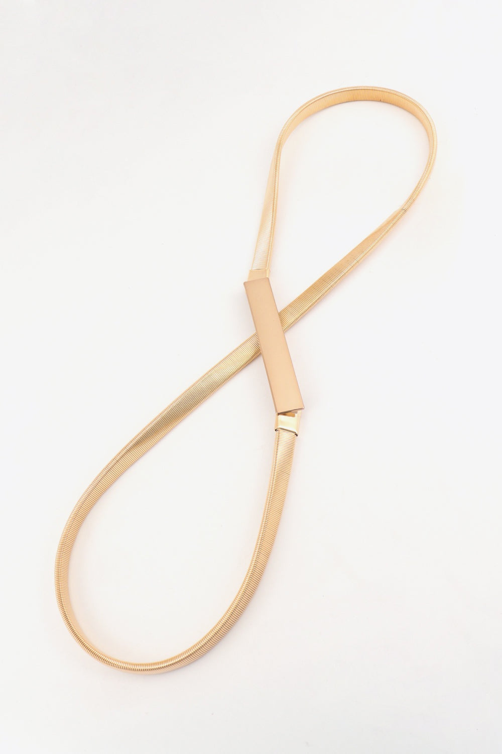 A gold-tone elastic iron skinny belt with a slender coiled profile and structured rectangular buckle, shown laid out in a long loop.