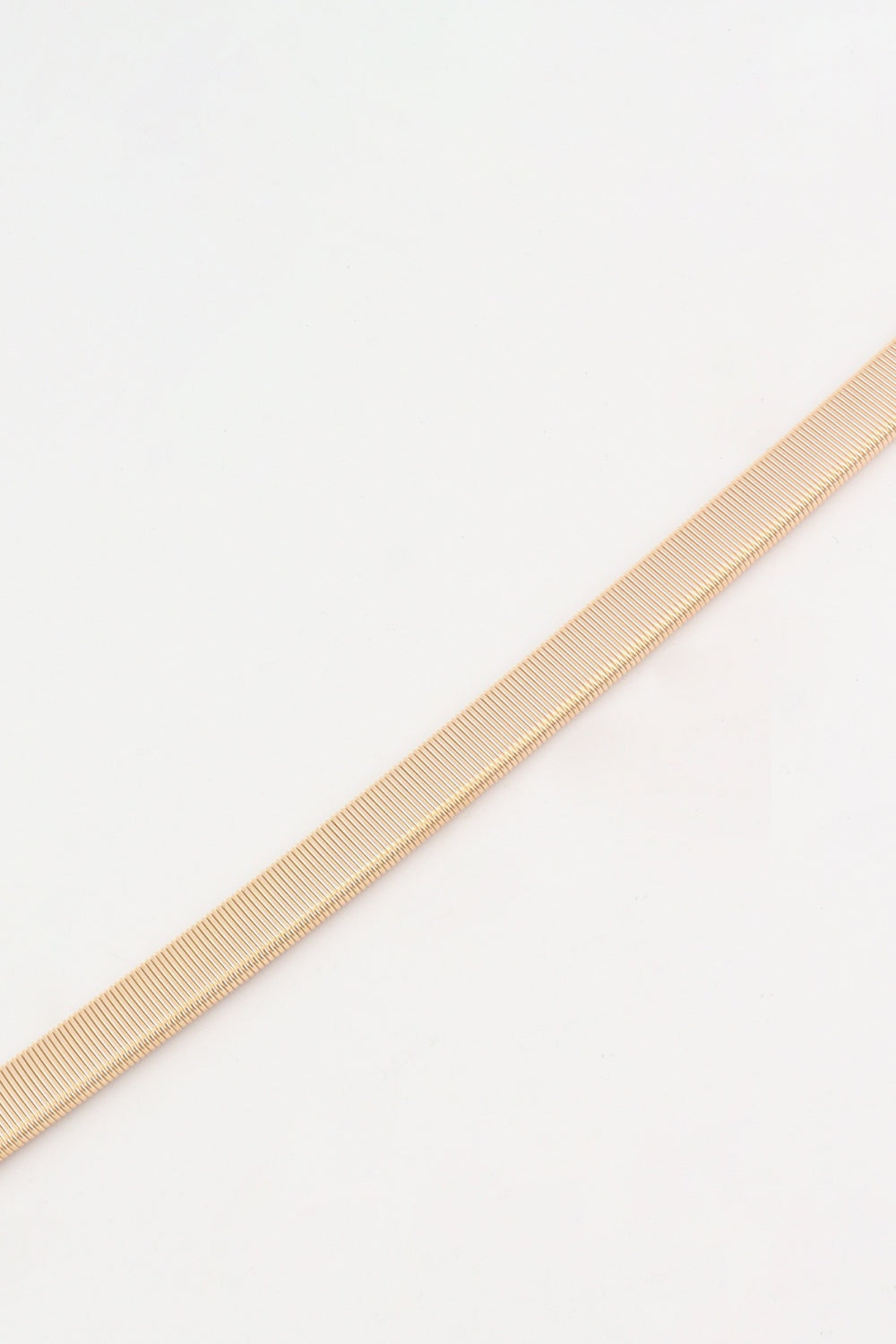 A slim gold-tone elastic iron belt with a finely ribbed, flexible construction, shown diagonally to highlight its sleek skinny profile.