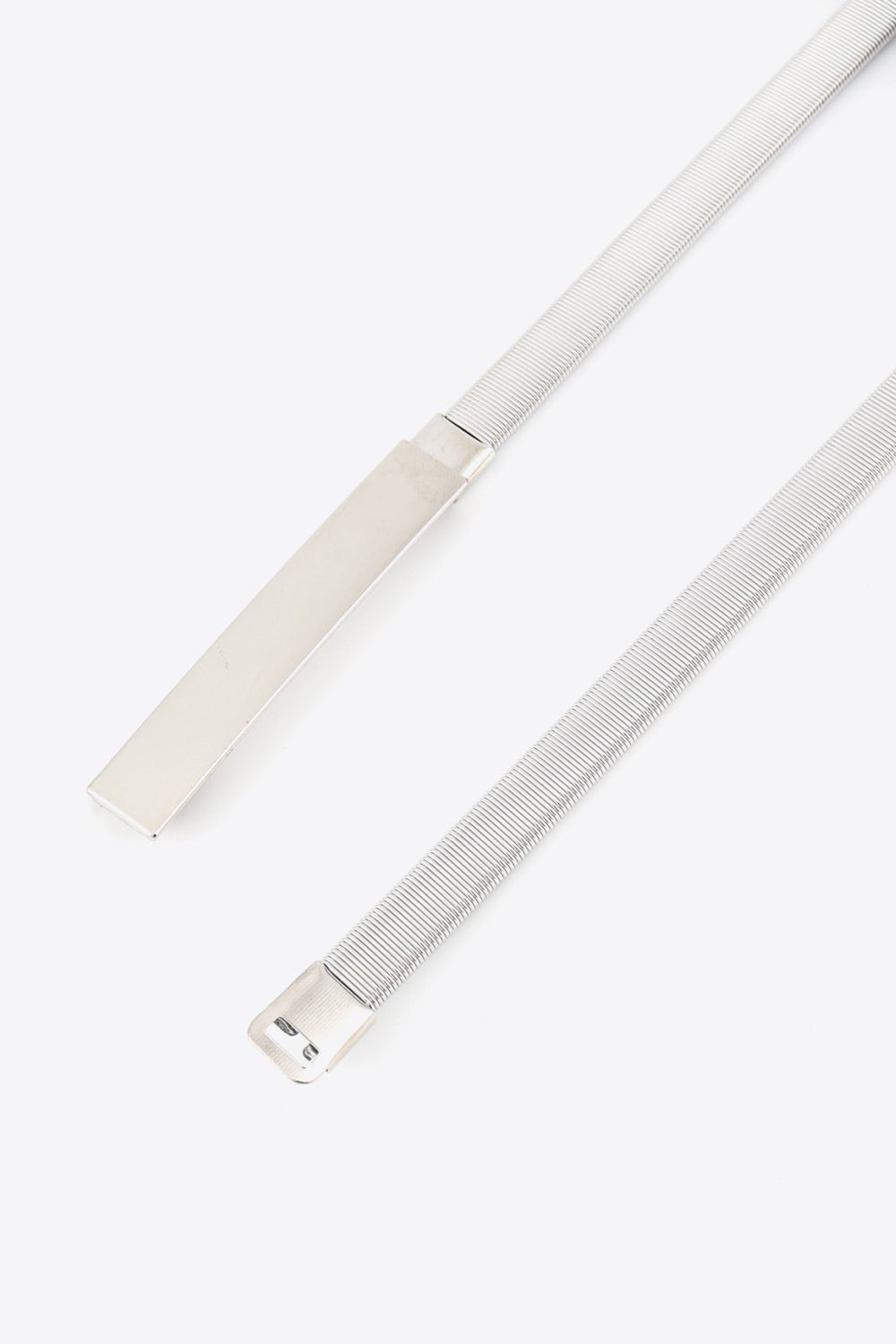 Slim silver elastic iron belt with a ribbed construction and sleek rectangular metal buckle, shown in two views to highlight its polished finish.