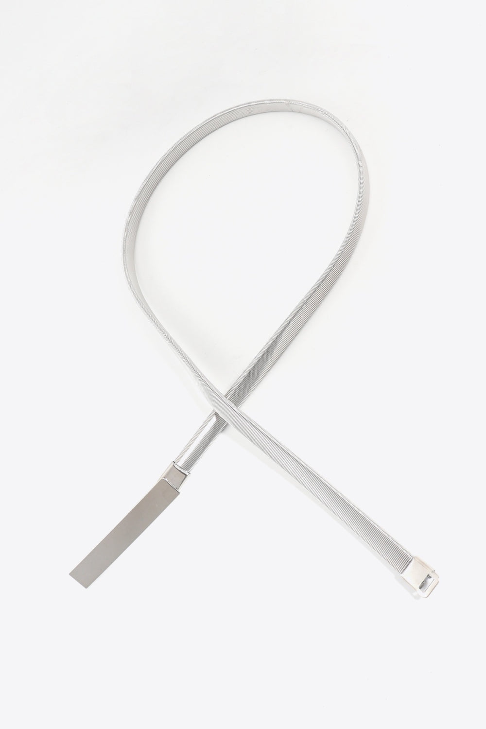 Slim silver elastic iron skinny belt shown in a loop, featuring a narrow flexible band and sleek rectangular buckle for polished waist definition.