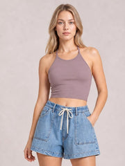 A model poses in light blue elastic waist denim shorts with a drawstring, large front pockets, belt loops, and a relaxed straight-leg silhouette.