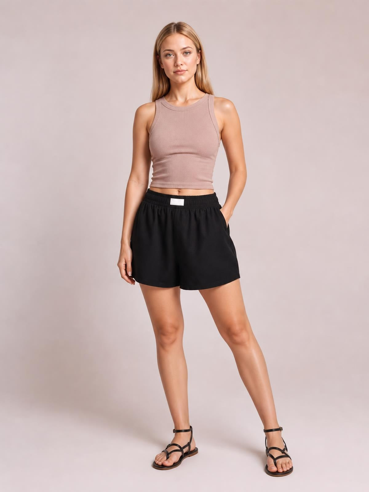 Model poses in black elastic waist shorts with a relaxed, loose silhouette, wide legs, and convenient side pockets.