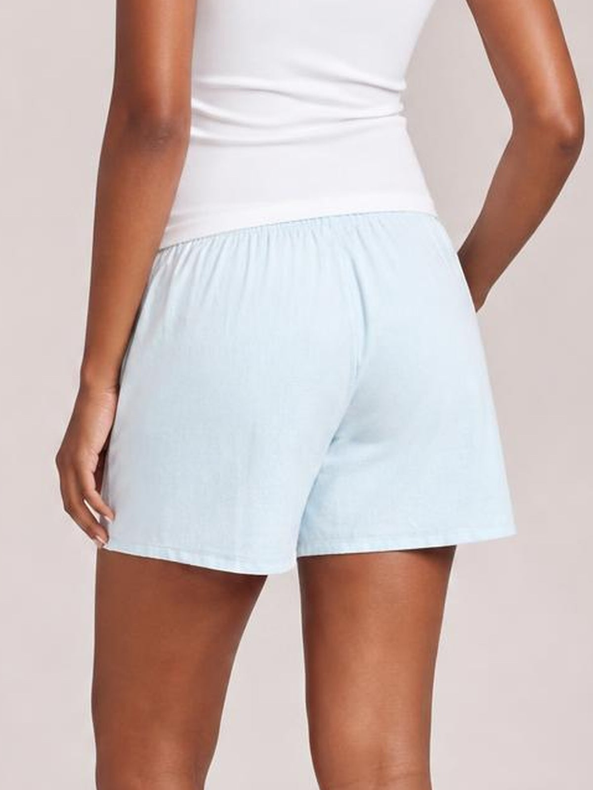 Model shown from behind wears light blue elastic waist shorts with a relaxed, straight-leg silhouette and convenient side pockets.